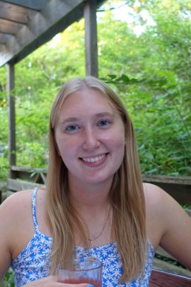 Maggie with a light blue shirt on and greenery in the background