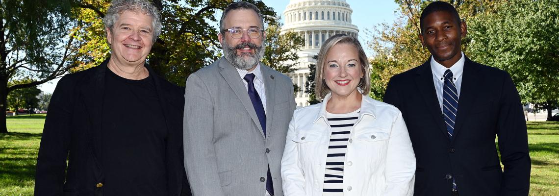 4 individuals standing for a photo with the Capitol in the background.